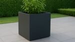 Schwarzer quadratischer Pflanzkübel aus Aluminium Ernesto Mobile auf einer Gartenterrasse, bepflanzt mit einer grünen Pflanze