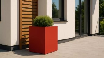 Roter hoher Pflanzkübel aus Aluminium Ernesto Mobile auf einer Terrasse vor einer Hausfassade, bepflanzt mit einem grünen Strauch