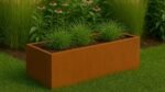 Ein rechteckiges Pflanzkübel ohne Boden aus Cortenstahl Rechteckig 150cm x 50cm x H 50 cm (Corten Frame 19) steht auf grünem Gras, das mit Ziergräsern bepflanzt ist; hohe Gräser und violette Sonnenhutblüten bilden eine friedliche Gartenkulisse.