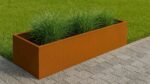 Ein rechteckiges Pflanzkübel ohne Boden aus Cortenstahl Rechteckig 200cm x 40cm x H 40 cm Corten Frame 17 mit grünen Ziergräsern steht auf grauem Steinpflaster neben ordentlich getrimmtem Rasen in diesem modernen Garten im Freien.