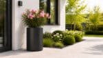 Schwarzer Aluminium-Pflanzkübel mit rosa Oleander vor einem modernen Haus, 60 cm Durchmesser und 80 cm Höhe, auf einer hellen Terrasse