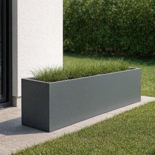 Ein langer, rechteckiger Pflanzkübel XXL aus Fiberglas, gefüllt mit grünem Gras, sitzt auf grauen Fliesen neben einem weißen Gebäude. Im Vorder- und Hintergrund ist ein gepflegter Garten mit sattgrünem Rasen sichtbar.