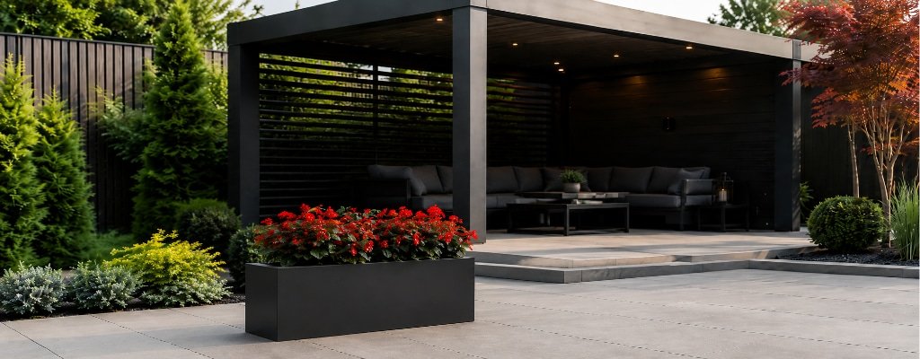 Schwarzer Aluminium Pflanzkübel mit roten Begonien auf einer modernen Terrasse vor einer eleganten Gartenpergola