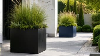 Moderne Fiberglas-Pflanzkübel in Schwarz und Blau mit grüner Bepflanzung auf einem hellen Gartenweg