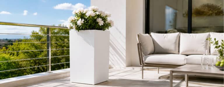 Weißer Fiberglas-Pflanzkübel mit weißen Blüten auf einem sonnigen Balkon