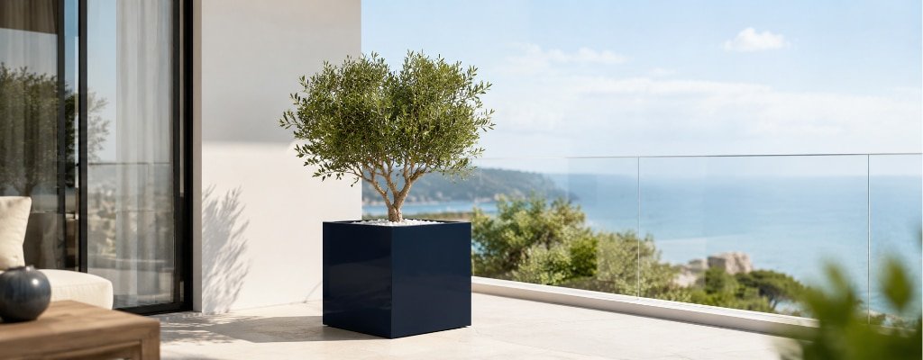 Dunkelblauer Fiberglas-Pflanzkübel mit kleinem Zierbaum auf einem sonnigen Balkon