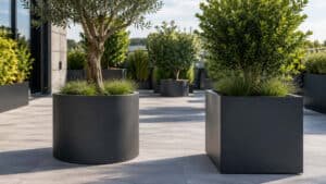 Runder und eckiger Aluminium Pflanzkübel mit Bäumen und Gräsern auf einer modernen Terrasse