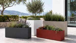 Pflanzkübel aus Aluminium in Anthrazit, Weiß, Beige und Rot mit unterschiedlicher Bepflanzung auf einer modernen Terrasse