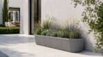Beton-Pflanzkübel mit Ziergräsern, Lavendel und heller Bepflanzung auf einer modernen Terrasse