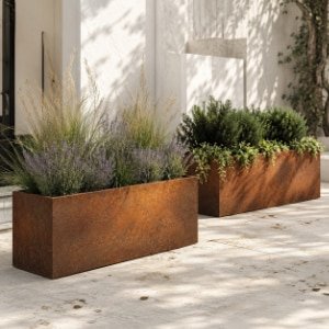 Cortenstahl-Pflanzgefäße mit Lavendel, Ziergräsern und grünen Sträuchern auf einer hellen Terrasse