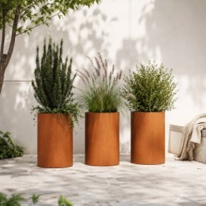 Cortenstahl-Pflanzgefäße mit verschiedenen grünen Pflanzen auf einer hellen, modernen Terrasse