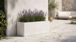 Fiberglas-Pflanzkübel mit blühendem Lavendel auf einer hellen Terrasse mit leicht verstreuten Blättern