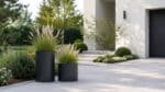 Fiberglas-Pflanzkübel mit blühendem Ziergras neben der Einfahrt vor einem modernen Haus