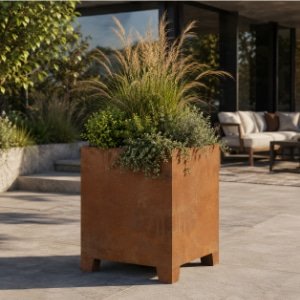Hoher quadratischer Cortenstahl-Pflanzkübel mit Ziergräsern und grünen Pflanzen auf einer modernen Terrasse