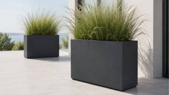 Pflanzkübel mit Ziergras auf einer hellen modernen Terrasse, einer im Vordergrund und einer im Hintergrund