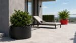 Pflanzkübel mit grünen Pflanzen auf einer modernen Terrasse neben einer Sonnenliege