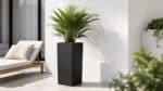 Hoher schwarzer Fiberglas-Pflanzkübel mit grüner Palme auf einer hellen modernen Terrasse