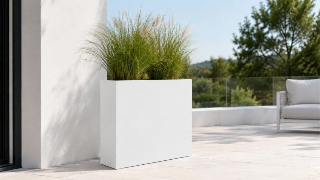 Weißer rechteckiger Fiberglas-Pflanzkübel mit grünem Ziergras auf einer hellen Terrasse