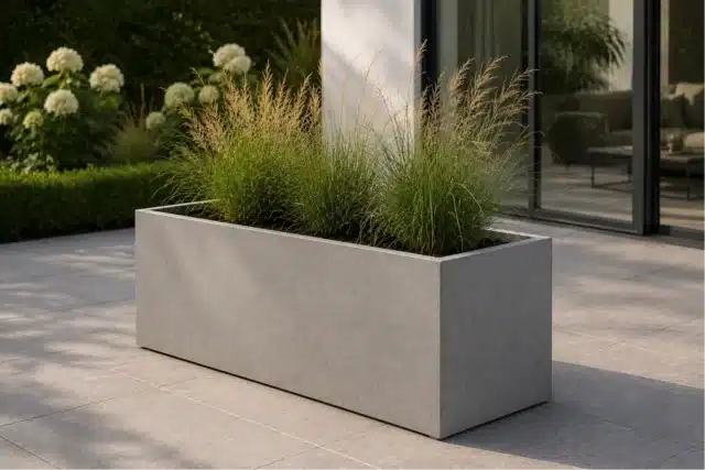 Rechteckiger Pflanzkübel aus Beton mit Ziergräsern auf einer modernen Terrasse